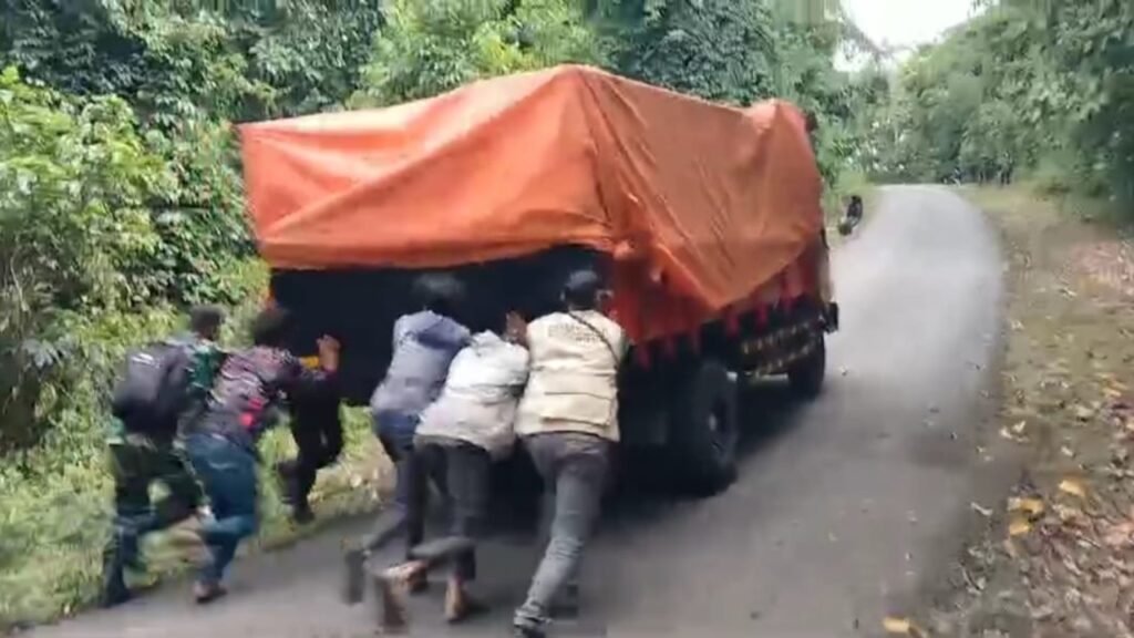 Petugas saat mendorong truk pengangkut Logistik Pemilu ke Desa Rarak Ronges, Kecamatan Brang Rea, Kabupaten Sumbawa Barat mengalami kendala saat memasuki tanjakan menuju desa tersebut, Selasa (13/2/2024).