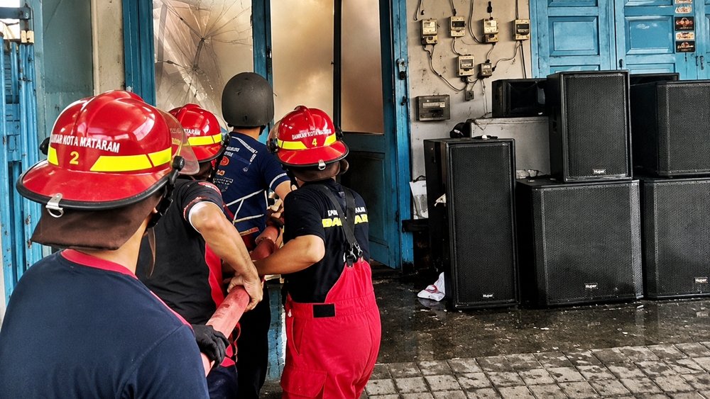 Petugas Damkarmat Kota Mataram melakukan penanganan kebakaran di gudang Rocket Music, kawasan Cakranegara, Kota Mataram, Selasa (25/8/2026). Kebakaran tersebut menyebabkan kerugian material sementara ditaksir sekitar Rp800 juta. Foto: Istimewa/KickNews.