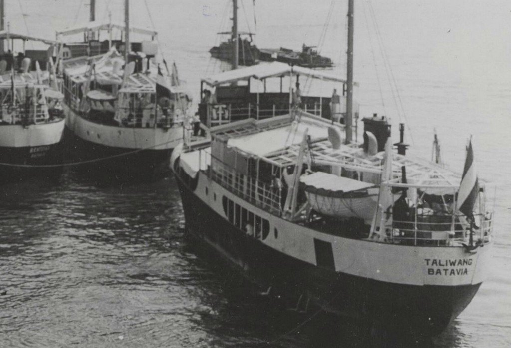 Kapal pesisir Taliwang dengan pelabuhan registrasi Batavia bersandar bersama kapal sejenis pada 1947. Kapal berbadan baja ini berlayar dari Rotterdam menuju Indonesia dan kemudian digunakan untuk mengumpulkan kopra di kawasan timur Indonesia. (Dok. Marhisdata/Kombuispraat)