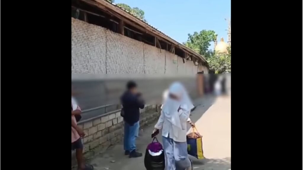 Seorang santriwati membawa barang bawaan saat meninggalkan pondok pesantren di Desa Bunkate, Kecamatan Jonggat, Lombok Tengah, Senin (22/9/2026). Sejumlah wali santri menjemput anak mereka setelah dugaan kekerasan seksual di lingkungan pesantren tersebut viral. (Foto: tangkapan layar)