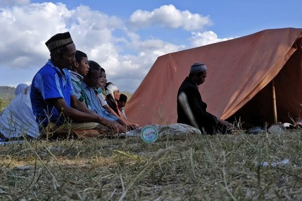 Warga melaksanakan salat di dekat tenda pengungsian saat rangkaian gempa Lombok 2018. Gempa susulan yang terus terjadi membuat banyak warga bertahan di ruang terbuka selama berhari-hari. Foto: Arsip kicknews.today